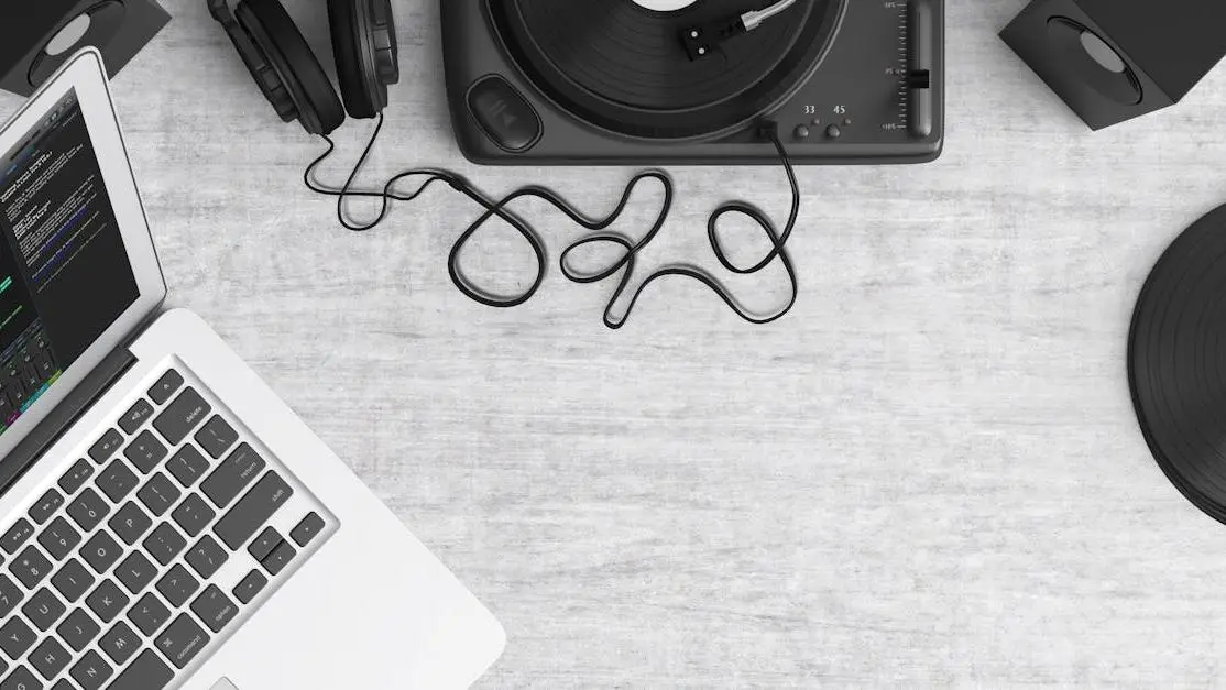 Flat lay van Beginners-DJ-apparatuur: laptop, koptelefoon, draaitafel en speakers op een bureau