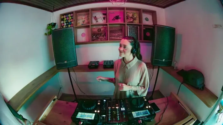 Vrouwelijke DJ mixt tracks in een gezellige studio in Brazilië tijdens een DJ-cursus, omringd door apparatuur