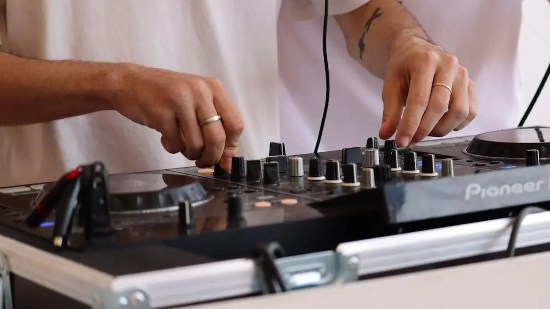 DJ mixt met controller; gefocuste handen en gear – DJ-lessen voor beginners bij mij in de buurt.